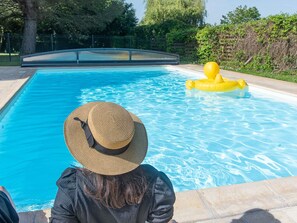 Una piscina con agua azul cristalina, rodeada de una valla y follaje.