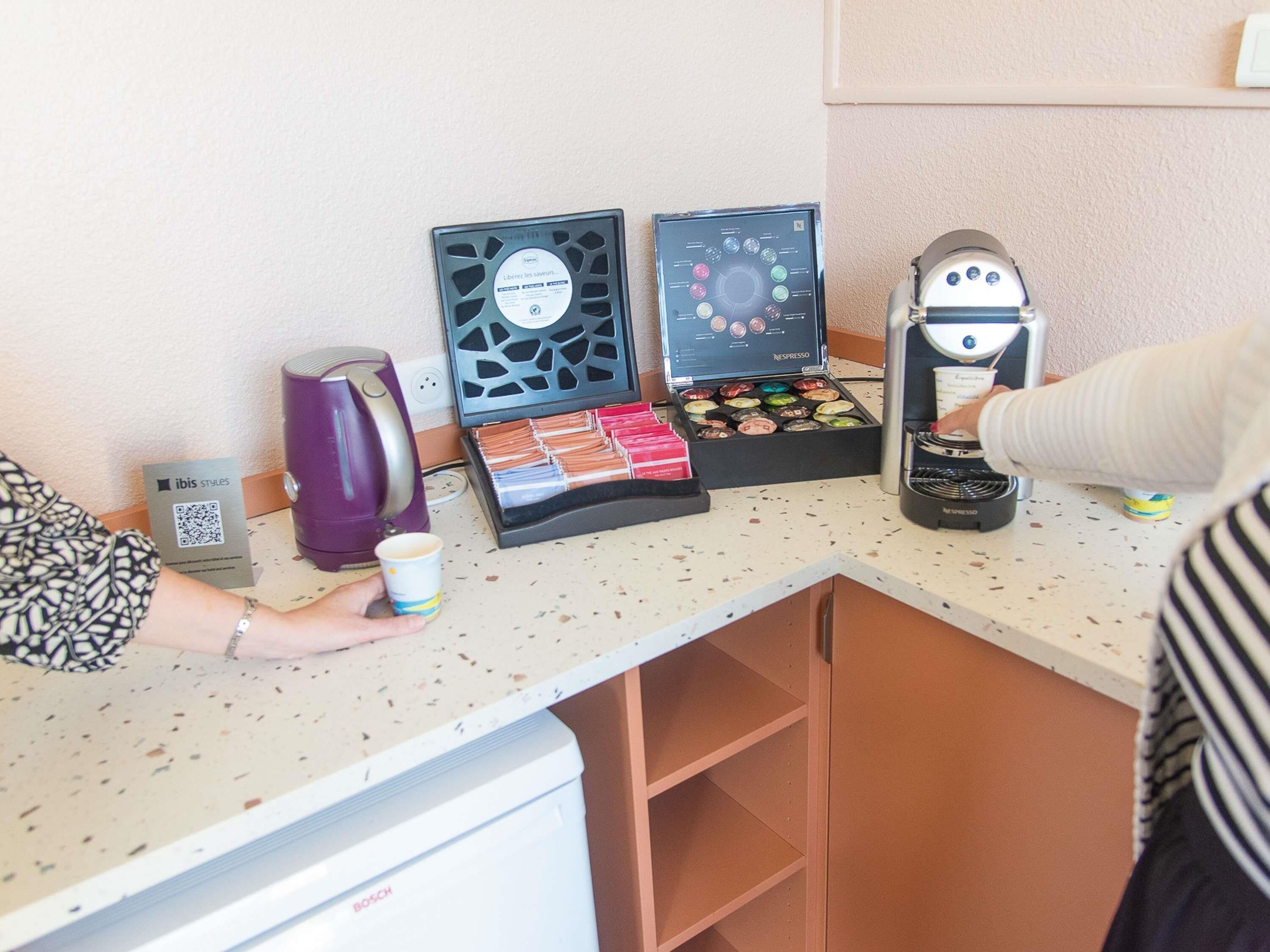 A coffee station with a coffee maker, a box of pastries, and a QR code for a coffee shop.