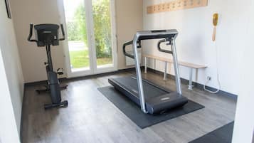 Un gimnàs amb cinta de córrer, bicicleta d'exercici i una banca.