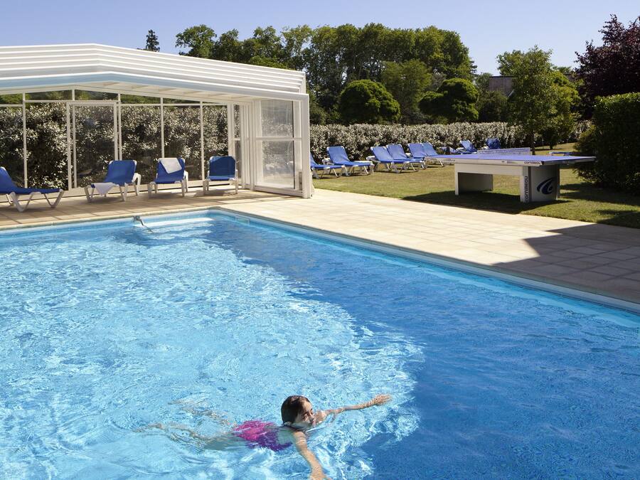 Een seizoensgebonden buitenzwembad, ligstoelen bij het zwembad