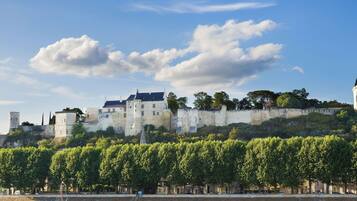 A historic castle with a river in the foreground and a clear sky.