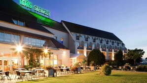 A hotel with a prominent 'ibis St. Gallen' sign, outdoor seating area, and a well-lit facade.