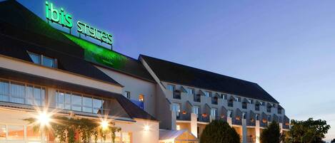 Un hôtel reconnaissable à son panneau « ibis St. Gallen » bien visible, doté d’un espace extérieur aménagé et d’une façade bien éclairée.