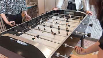 A foosball table with players, a wall with a decorative design, and a person holding a camera.