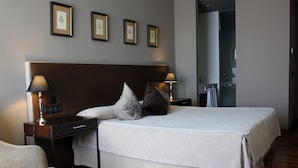 A neatly arranged hotel room with a large bed, two bedside tables with lamps, a chair, and framed pictures on the wall.