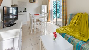 Una sala de estar moderna con televisor, una mesa de comedor y un sofá con una manta amarilla.