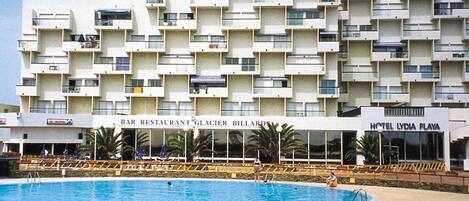 A hotel with a swimming pool, multiple balconies, and a bar restaurant.