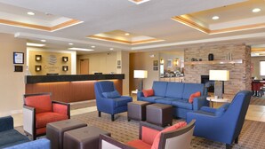 A hotel lobby with a reception desk, blue and red seating, a fireplace, and a patterned carpet. - Comfort Inn Evansville - Casper (Evansville)