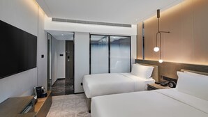 A modern hotel room with two beds, a flat-screen TV, a bedside table, and a wall-mounted light fixture. - Park Plaza Beijing Science Park (Beijing)