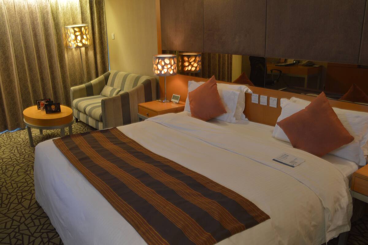 Een hotelkamer met een groot bed, een stoel, een tafeltje en twee lampen.