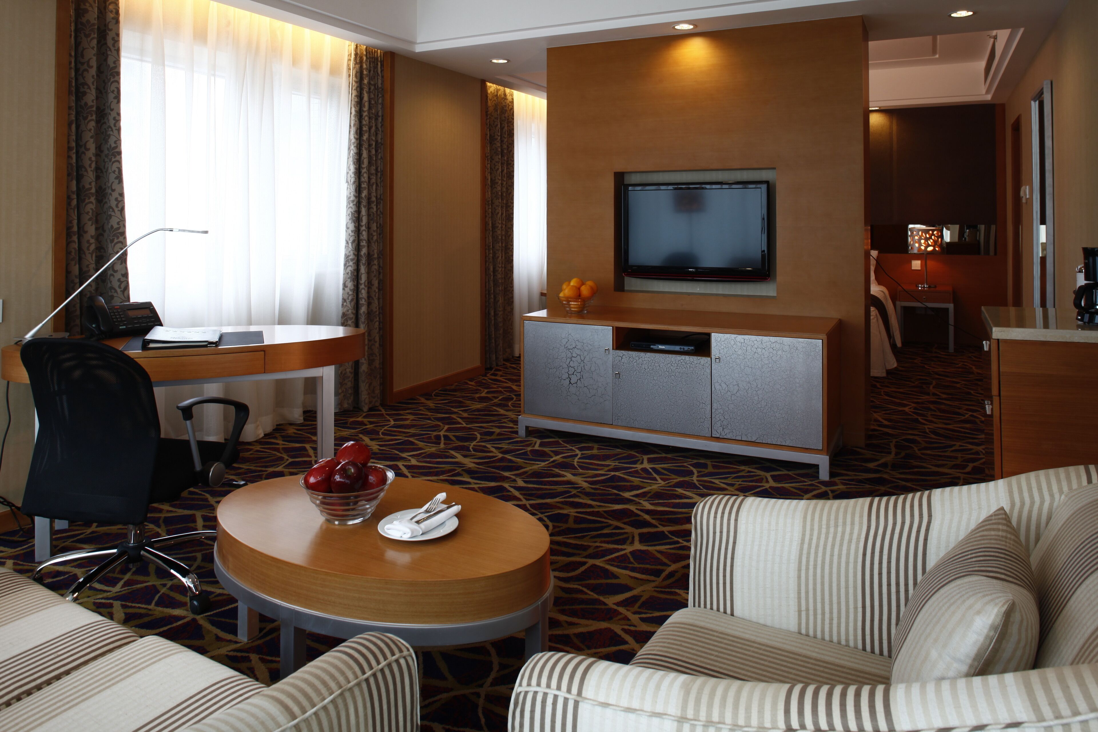 Ett hotellrum med TV, skrivbord, matplats och en sittgrupp med ett litet bord och stolar.