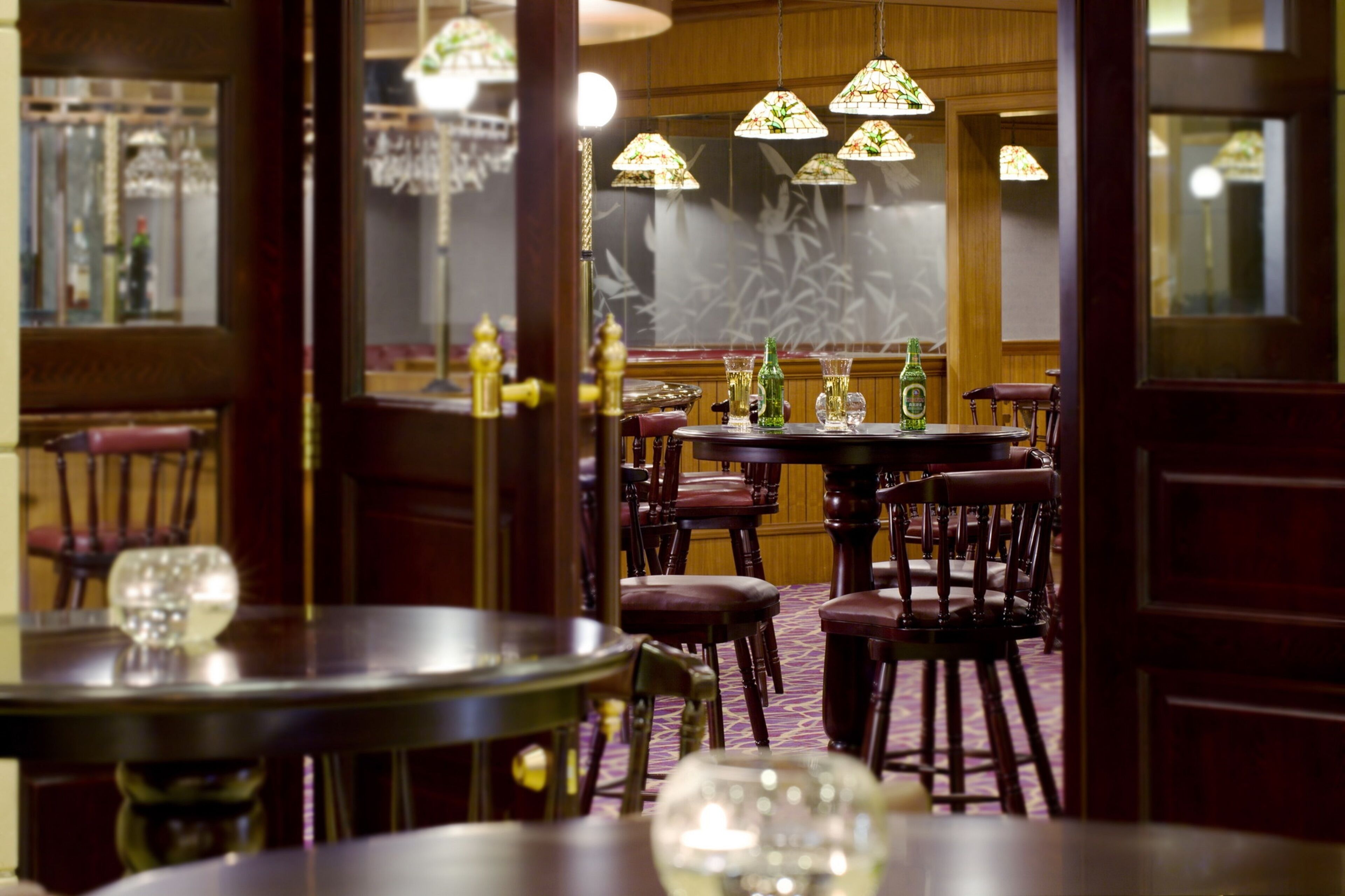 Een restaurantinterieur met houten meubels, ronde tafels en hanglampen.