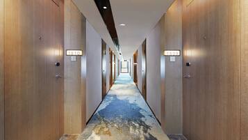 A hotel hallway with wooden doors, numbered room signs, and a patterned carpet.