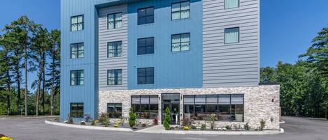 A modern hotel with a blue facade and a stone accent wall.