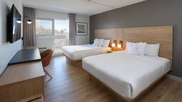 A hotel room with two beds, a desk, a chair, and a window with curtains.