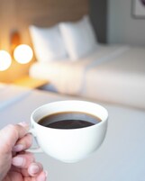 Una mano sosteniendo una taza blanca de café.