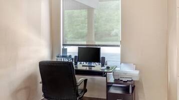 A home office setup with a desk, computer, chair, and printer.