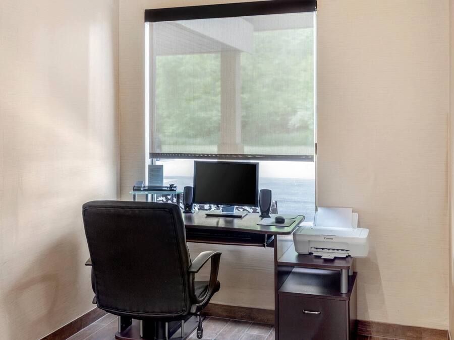 A home office setup with a desk, computer, chair, and printer.