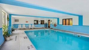 Une piscine intérieure avec des lignes de démarcation bien visibles, une bouée de sauvetage et des chaises longues disposées le long du bord de la piscine.