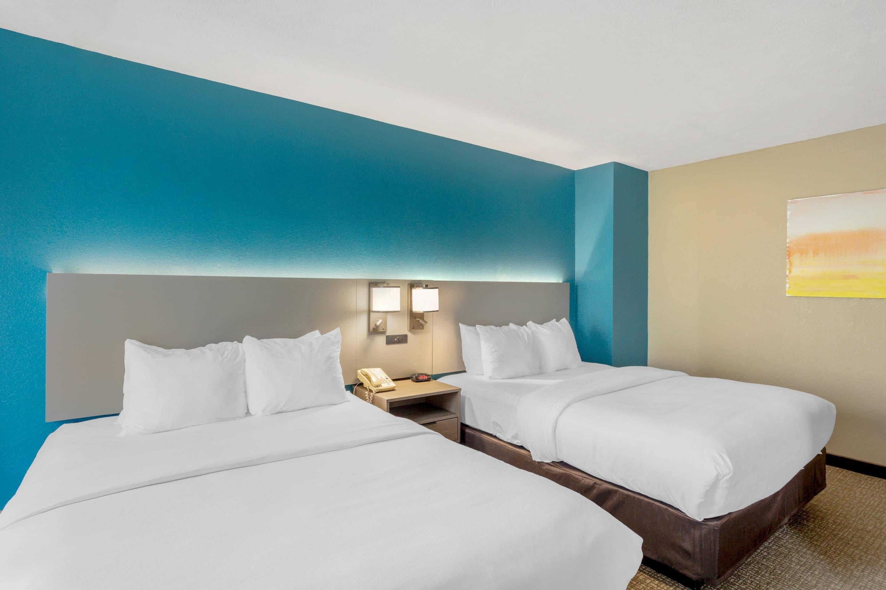 Ein Hotelzimmer mit zwei Betten, einem Nachttisch, einem Telefon und einer Wandleuchte.