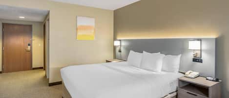 A hotel room with a large bed, bedside tables, a desk, and a phone.