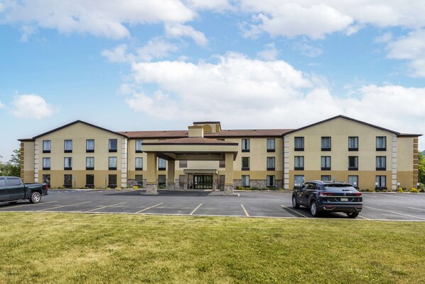 Un hôtel à plusieurs étages, doté d’une entrée principale, d’un parking et d’une pelouse à l’avant.