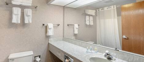 A modern bathroom with a marble sink, a toilet, a shower with a glass door, and multiple towel racks.
