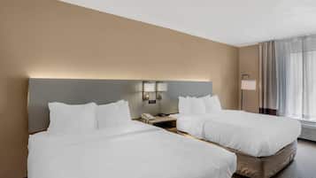 Una habitación de hotel con dos camas, una mesita de noche con un teléfono y una lámpara.