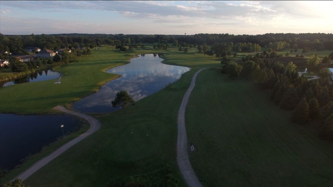 Vista aérea de un campo de golf con varios estanques, un camino serpenteante y vegetación circundante.