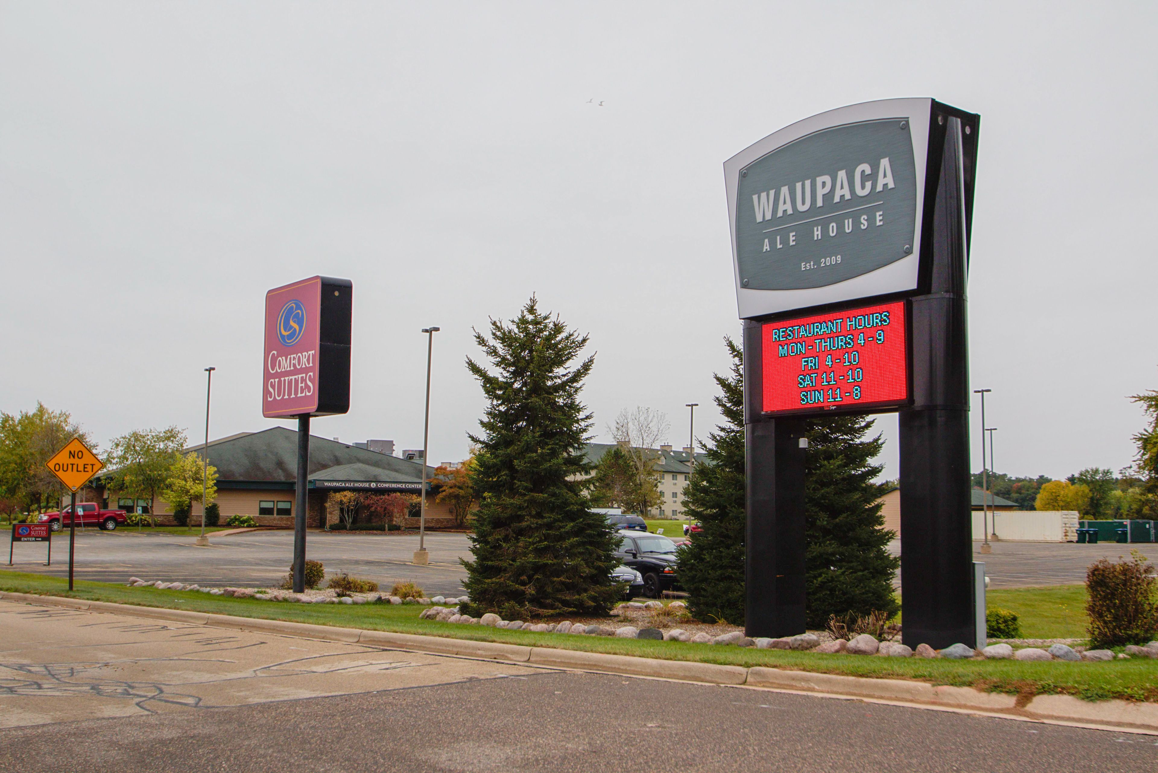 A hotel sign with the name 'Waupaca' and a sign for 'Comfort Suites'.