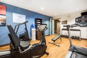 A gym with exercise equipment, a water dispenser, and a wall clock. - Comfort Suites at Par 4 Resort (Waupaca)