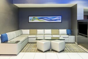 Una sala moderna con un sofá modular, una mesa de centro de vidrio y un televisor de pantalla plana.