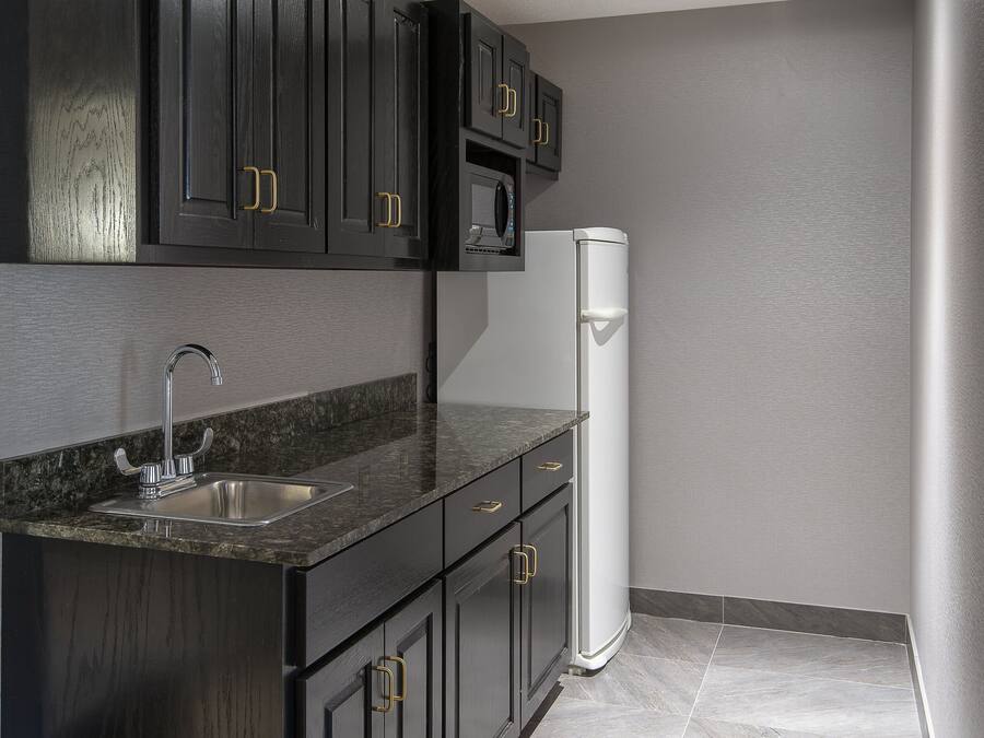 A modern kitchen with dark cabinetry, a stainless steel sink, and a white refrigerator.