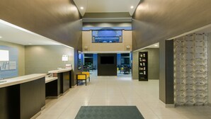 A hotel lobby with a reception desk, seating area, and a staircase leading to an upper level. - Holiday Inn Express & Suites Cooperstown by IHG (Cooperstown)