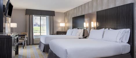 A hotel room with two beds, a desk, a TV, and a large window with curtains.