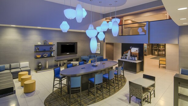 A modern hotel lobby with a central bar area, seating arrangements, and a television screen. - Holiday Inn Express & Suites Cooperstown by IHG (Cooperstown)