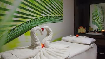 Experience serenity in this spa room, featuring a vibrant palm leaf artwork and a clean, relaxing atmosphere.