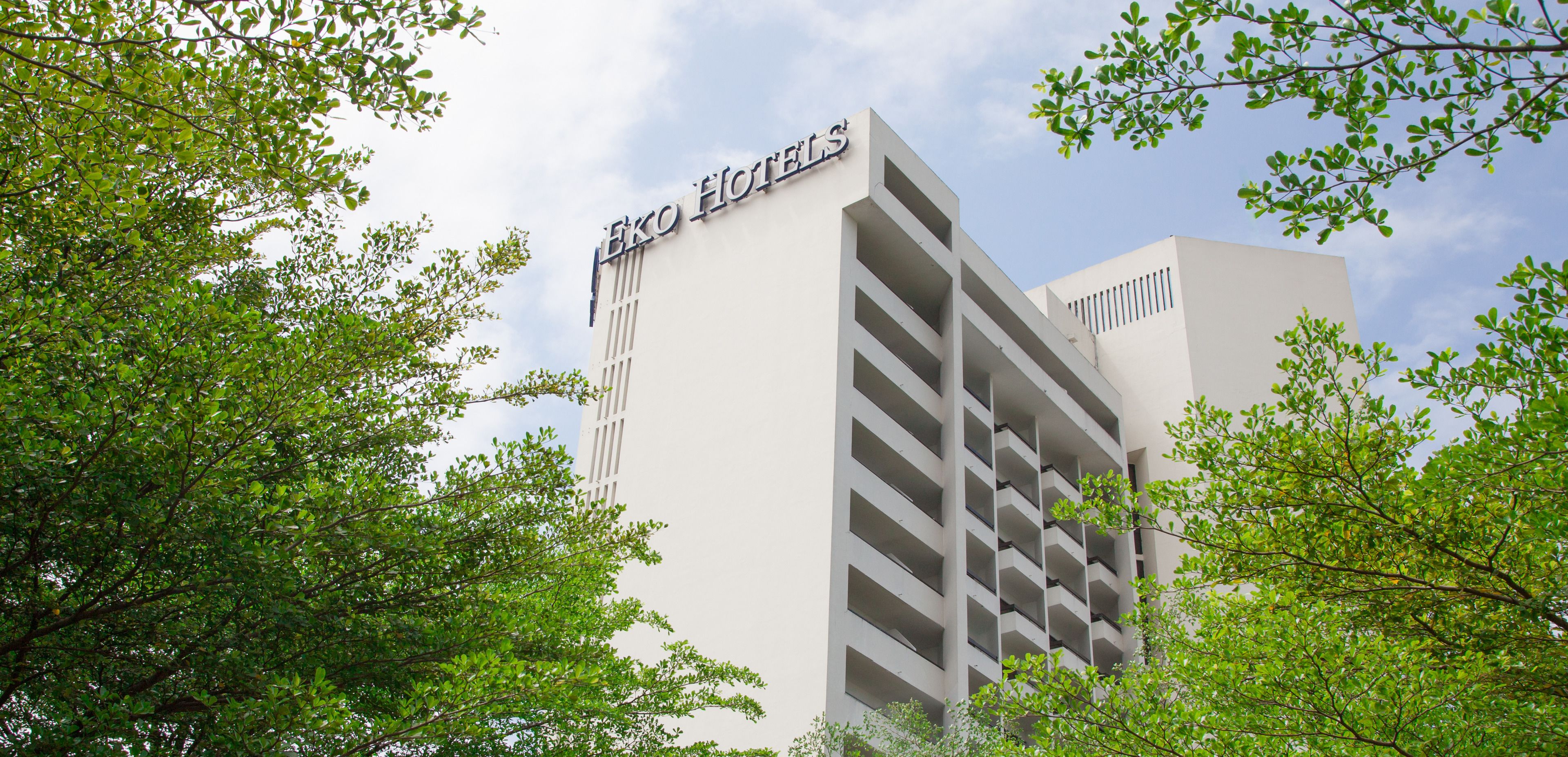 Un bâtiment d’hôtel avec une enseigne indiquant « Eko Hotels » et une architecture moderne agrémentée de balcons.