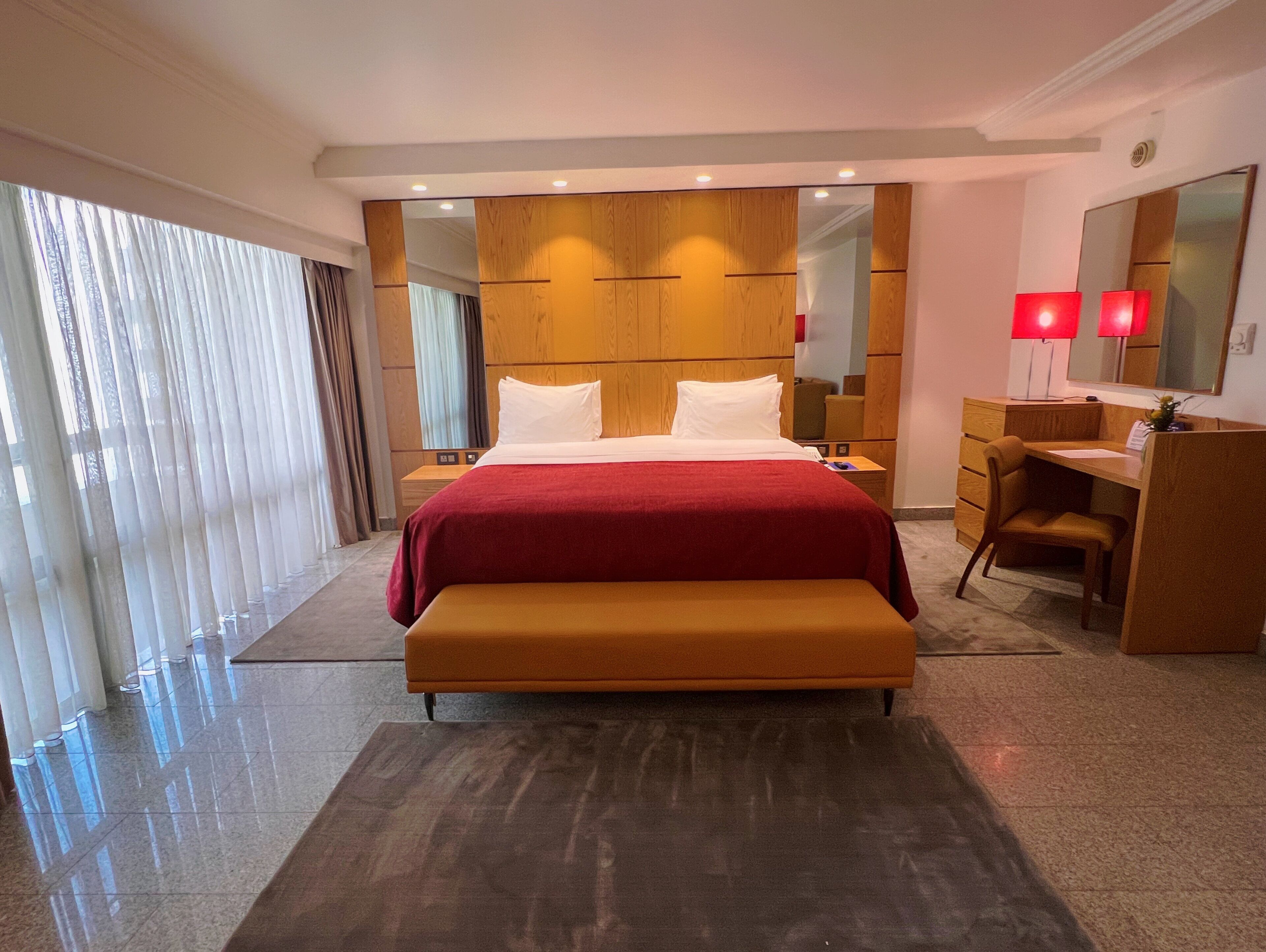 A modern hotel room with a large bed, a desk, and a chair.