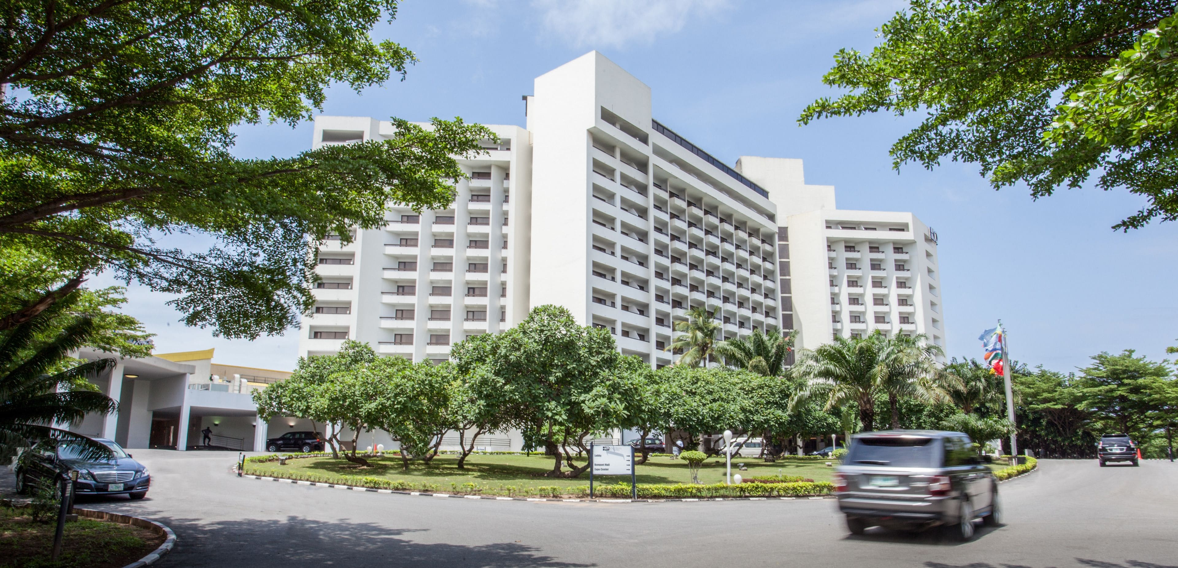 A multi-story hotel with a modern design, featuring a central courtyard with trees and a flagpole.