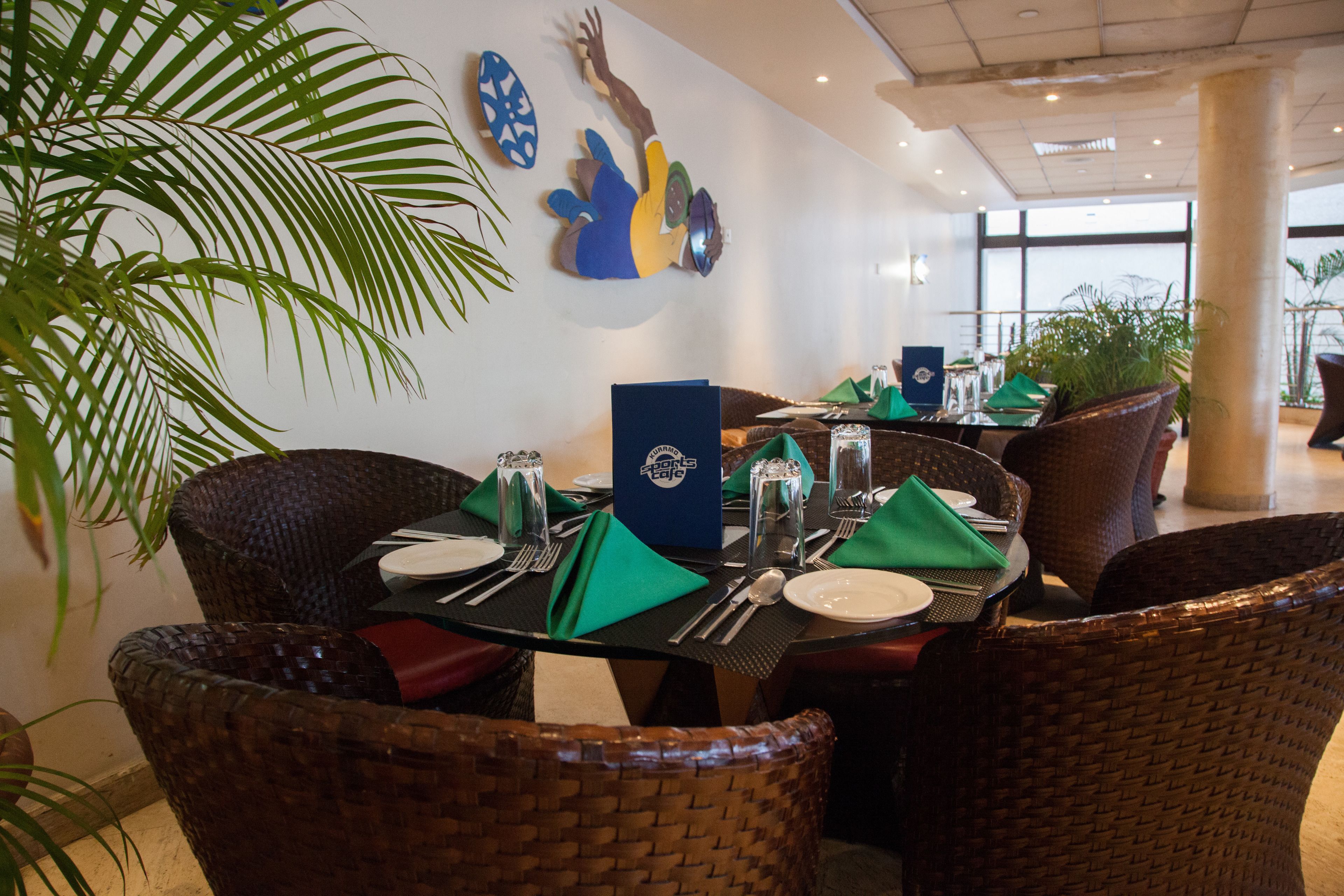 A dining area with wicker chairs, a table set with plates, cutlery, and green napkins.