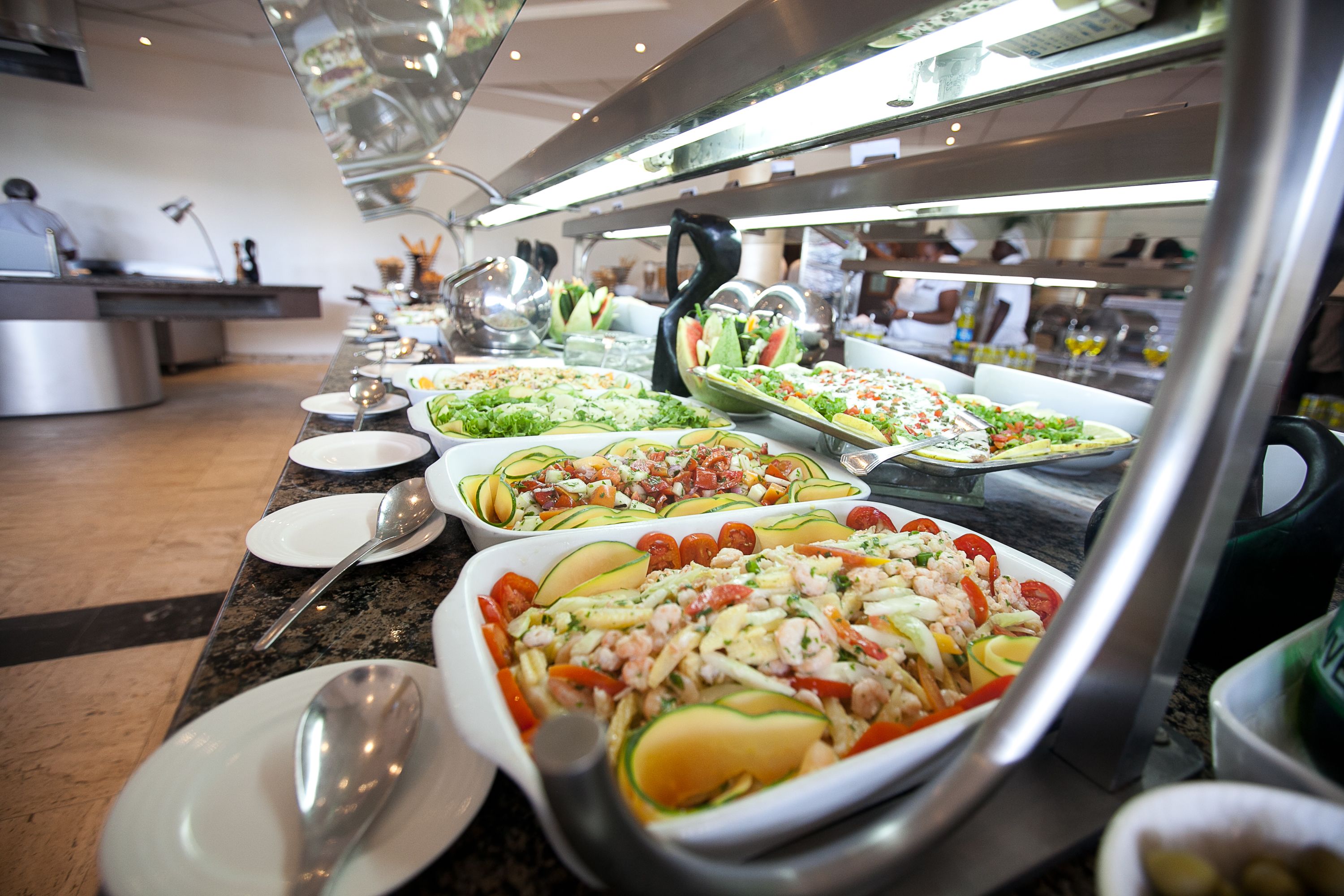 A buffet with various dishes, including salads, seafood, and pasta, arranged on a counter.