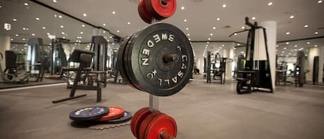 Zona de halterofilia con barra, discos de pesas y diverso equipamiento de gimnasio.