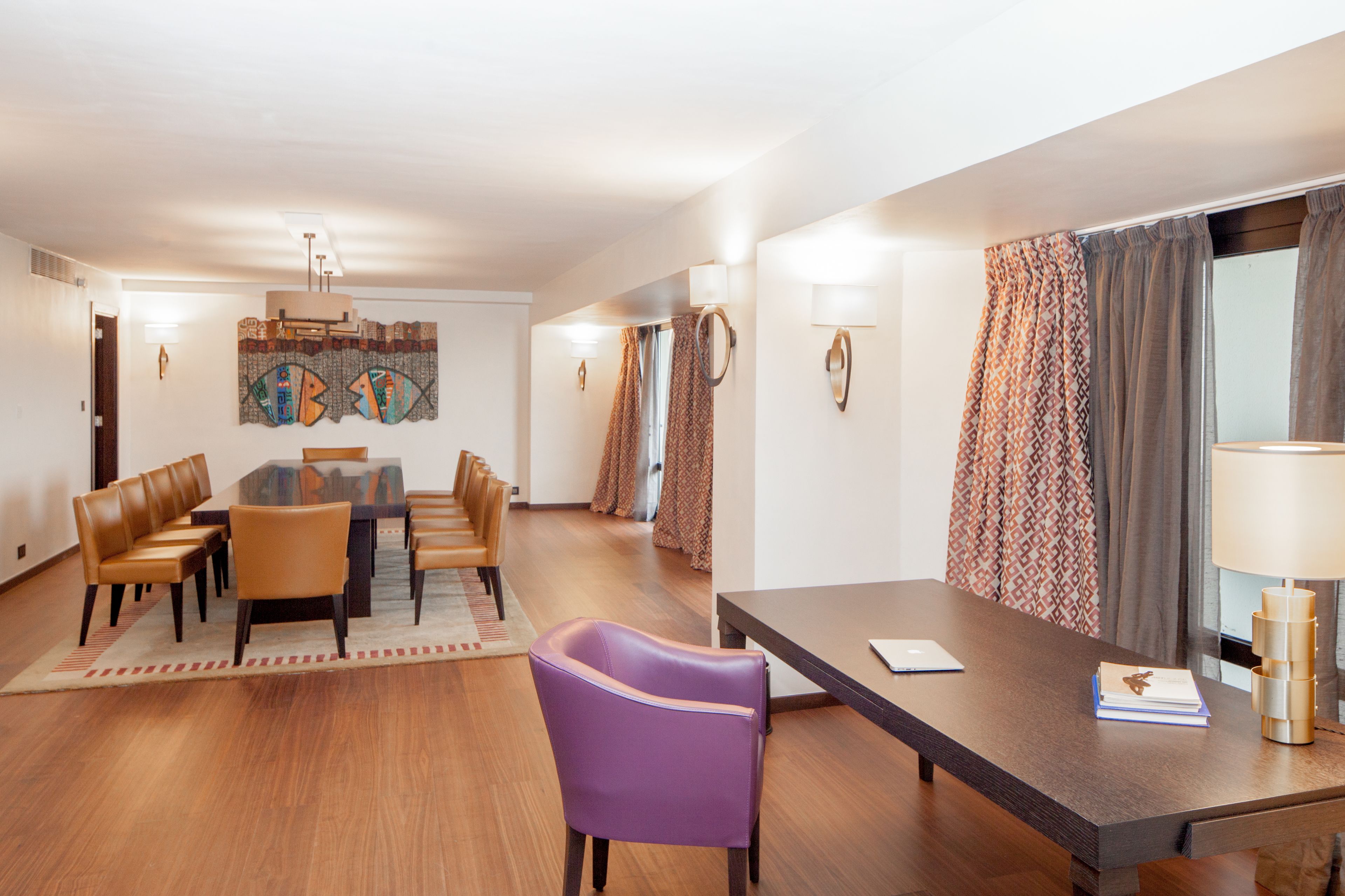 A hotel room with a dining area, a sofa, a table, and a lamp.