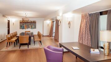 A hotel room with a dining area, a sofa, a table, and a lamp.