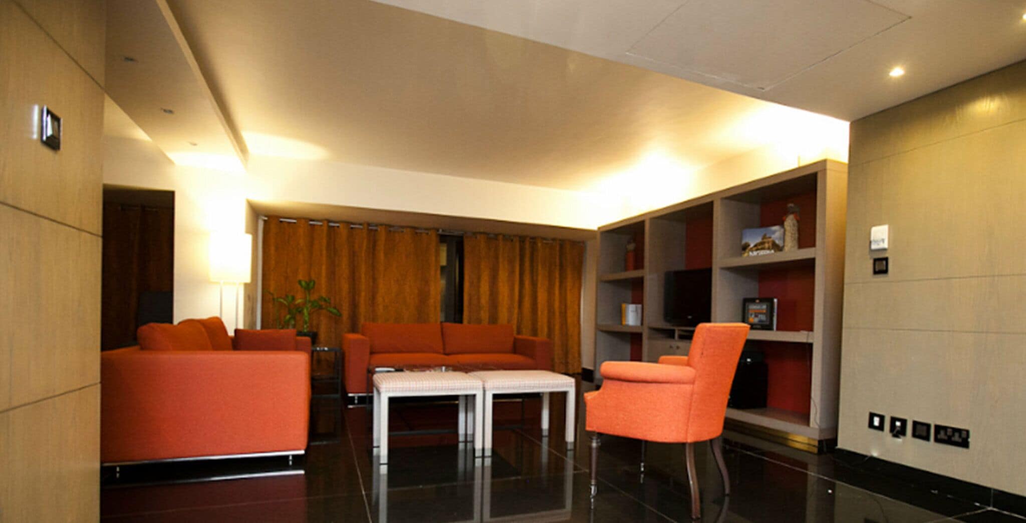 Una sala de estar moderna con sofás naranja, una mesa de centro blanca y una estantería.