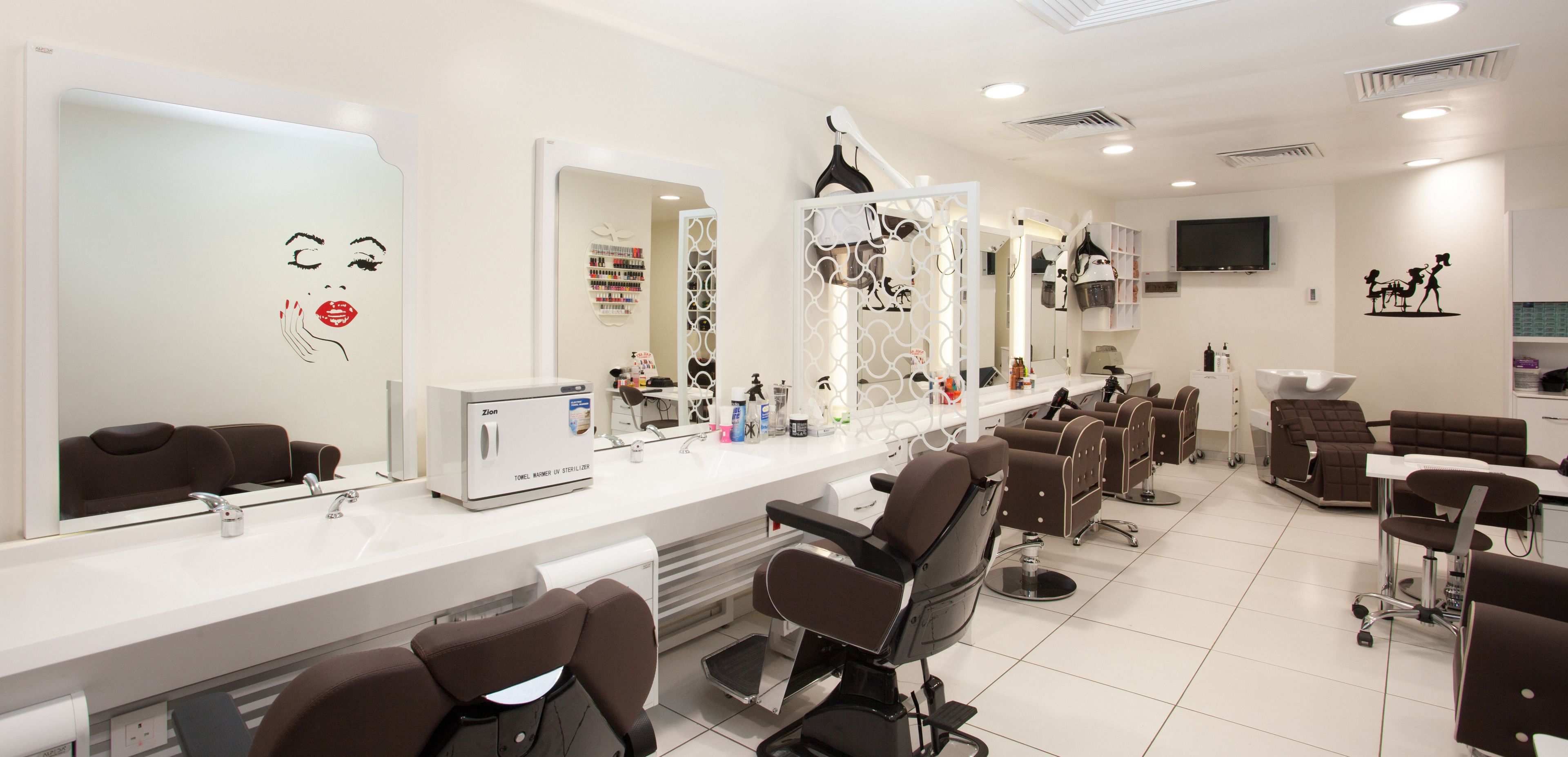 A modern salon with multiple hairdressing stations, a large mirror, and a variety of hair care products on the counter.