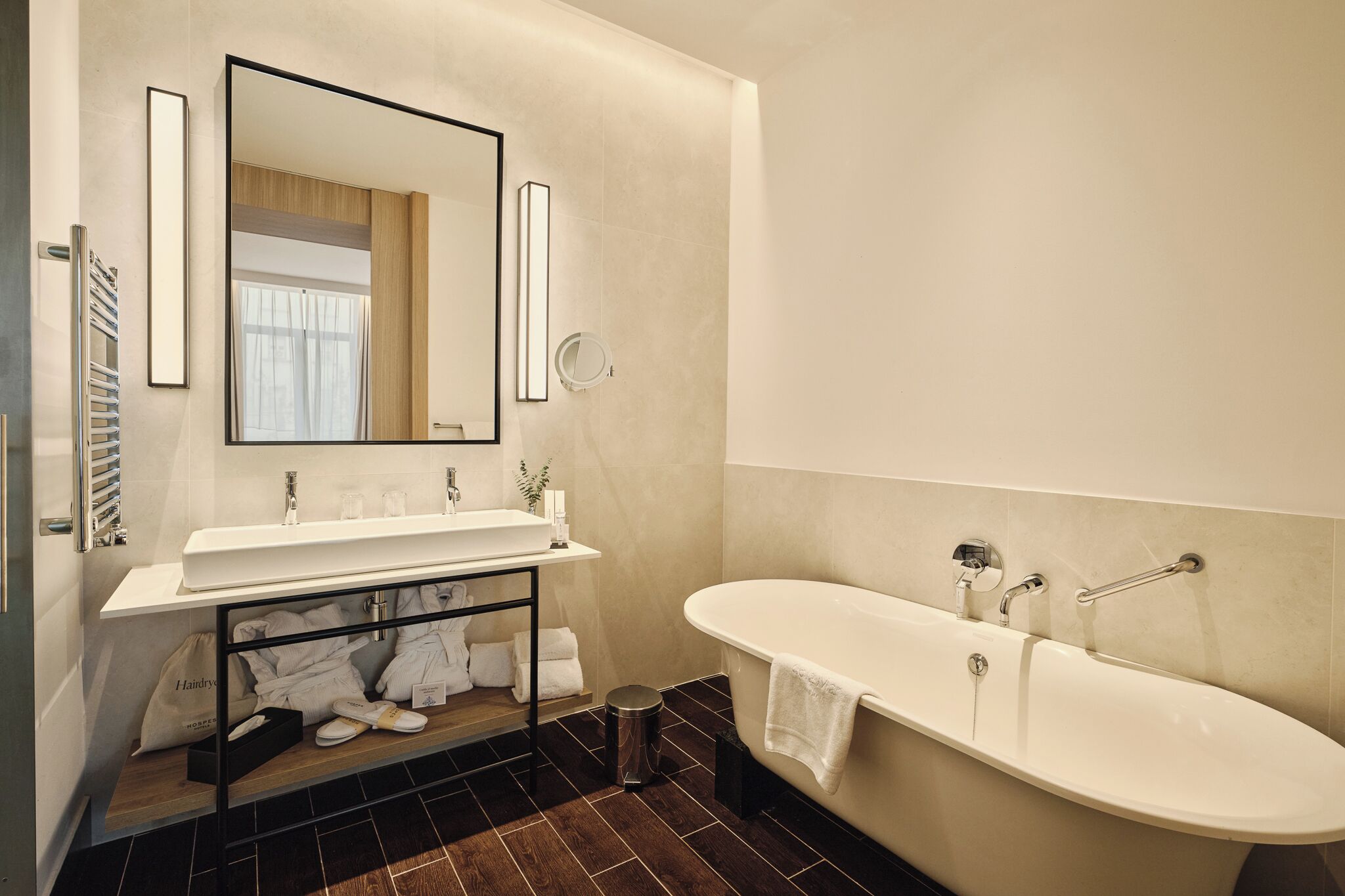 Un bagno moderno con una vasca da bagno ampia, un mobile lavabo con specchio e un porta asciugamani.