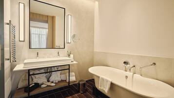 Un bagno moderno con una vasca da bagno ampia, un mobile lavabo con specchio e un porta asciugamani.