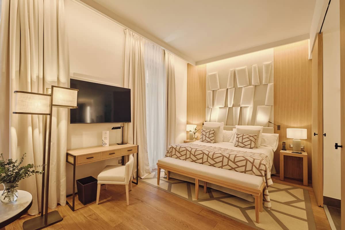 Une chambre d’hôtel moderne équipée d’un grand lit, d’un bureau, d’une télévision et d’un panneau lumineux fixé au mur.